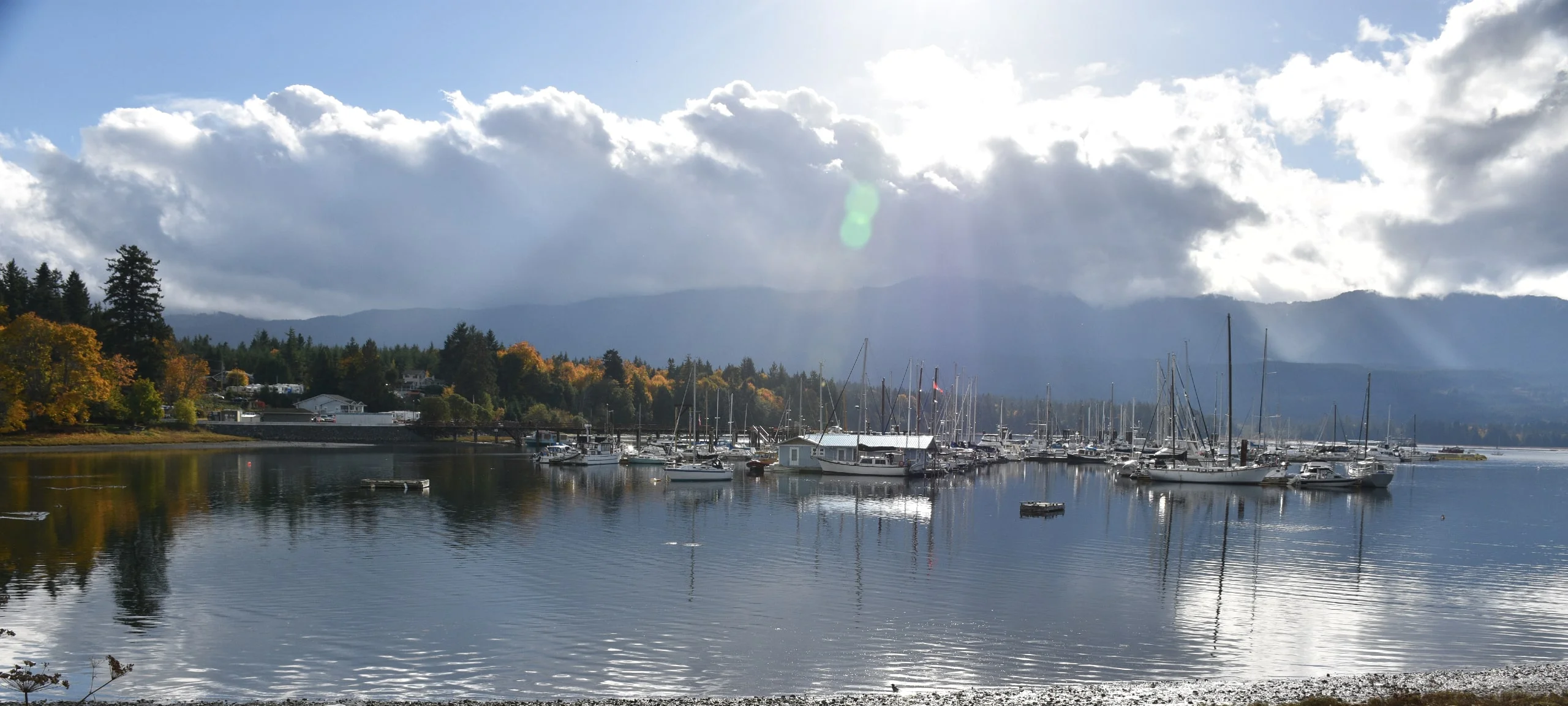 Sun and clouds over Deep Bay Marina, with mountains in distance