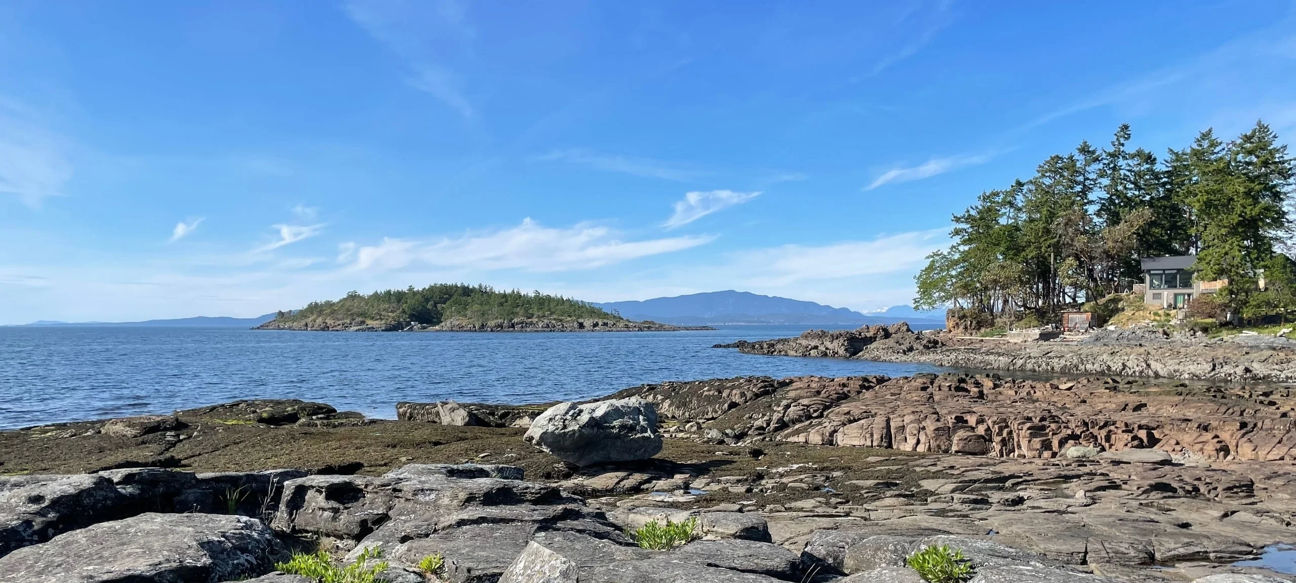 Rocks on the Nanoose Bay, BC shoreline with one house on the inlet