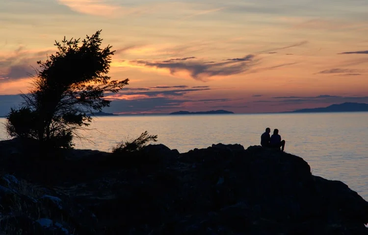 Silhouette of two people sitting at Neck Point Park beach during sunset
