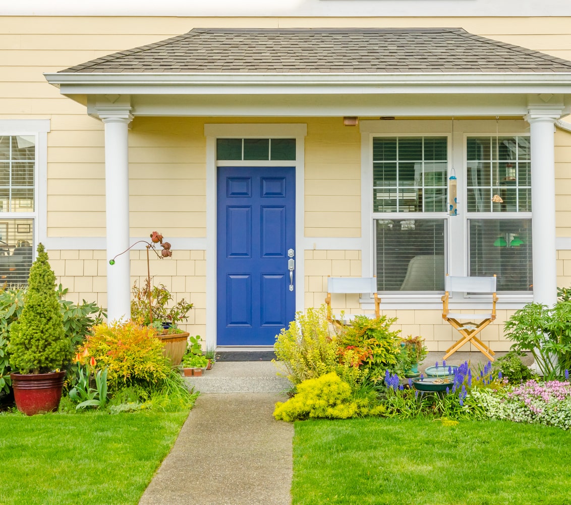 Blue front door of yellow house with porch
